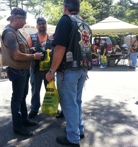 Bikers holding yellow bags advertising motorcycle attorneys and motorcycle awareness. The bags are full of giveaways