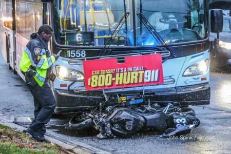 Personal injury lawyer billboard advertising 1-800-HURT-911 on the front of a bus overhanging a motorcycle hit by the bus