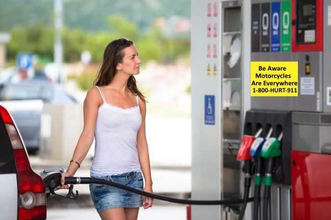 a woman looking at a motorcycle awareness sign on a gas pump advertising personal injury lawyers at 1-800-HURT-911®